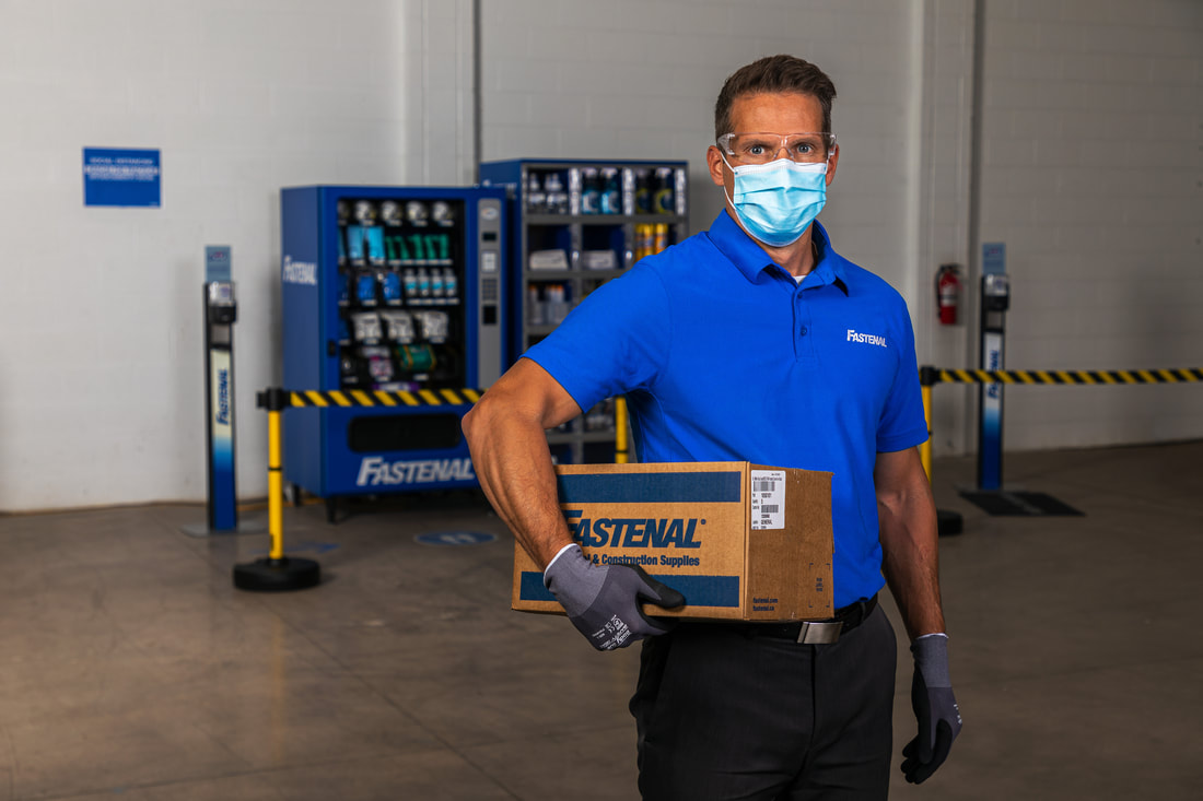 Fastenal employee standing in front of vending machine with mask on
