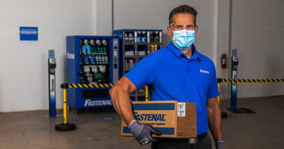 Masked Fastenal employee in front of vending machine